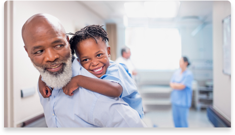 Mann und Enkelin lächeln im Krankenhausflur